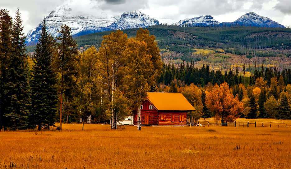 Meadow and cabin with Rocky Mountains in background