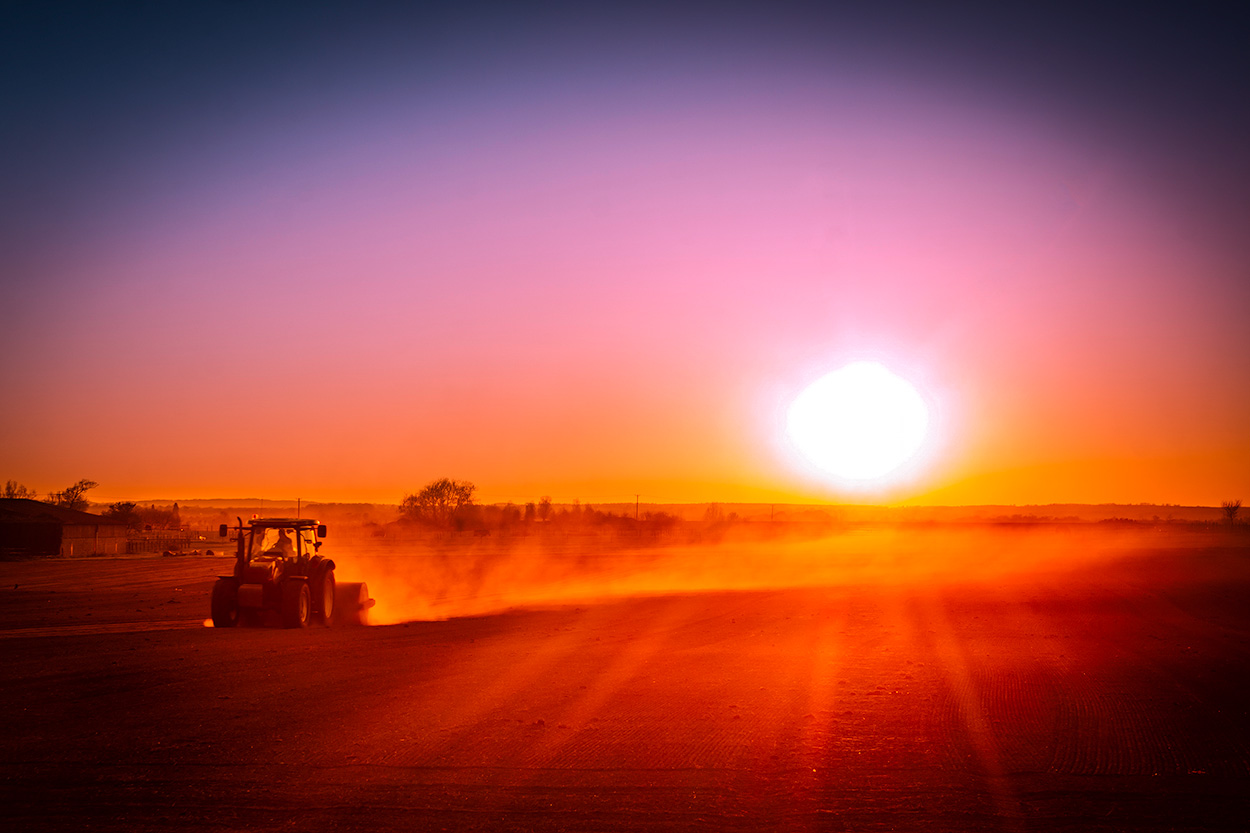 tractor in field at sunset