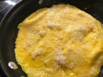 Sprinkle cheese into omelette