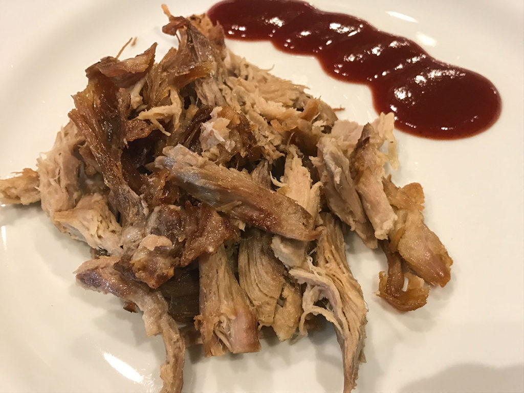 Pulled pork from a Boston butt roast served with some barbecue sauce on the side
