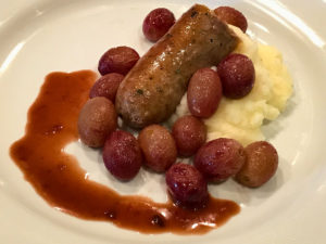 Sausage and grapes served with garlic mashed potatoes and a little pan gravy
